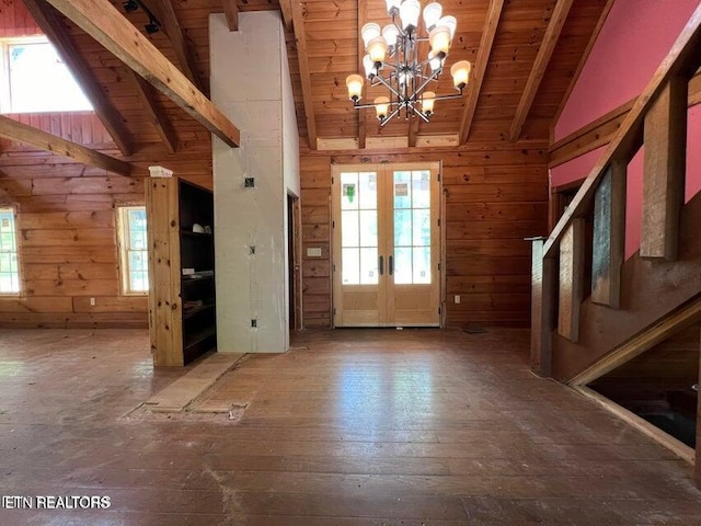foyer featuring stairway, wood ceiling, an inviting chandelier, wood walls, and beam ceiling