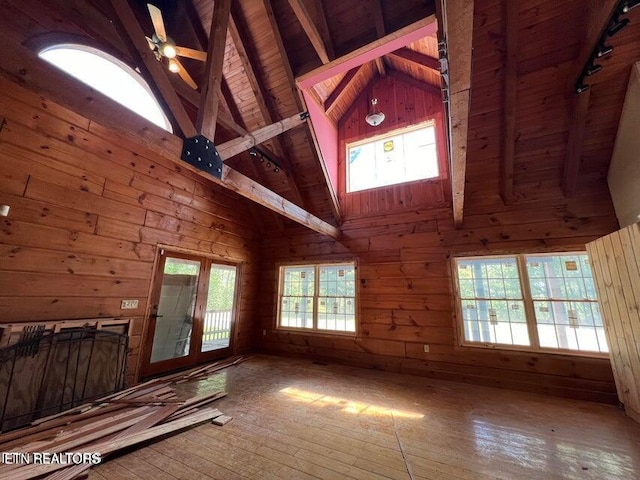 unfurnished living room with beam ceiling, wooden ceiling, wooden walls, and high vaulted ceiling