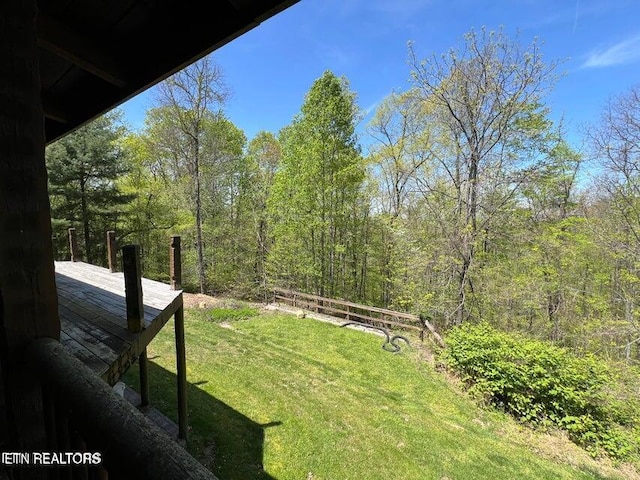 view of yard featuring a wooden deck and a wooded view