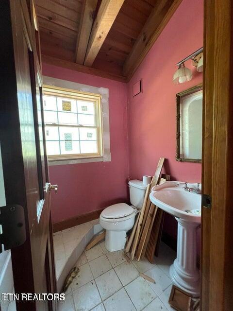 half bathroom featuring toilet, wood ceiling, vaulted ceiling with beams, and tile patterned floors