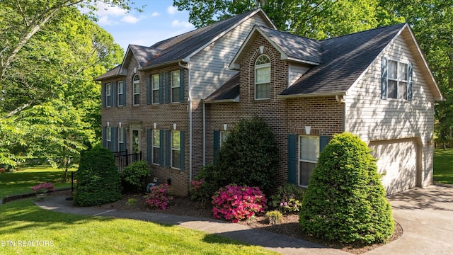 view of property exterior featuring brick siding, a garage, a yard, and driveway