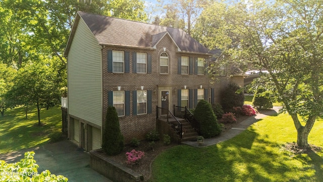 colonial inspired home with a front yard, brick siding, a shingled roof, concrete driveway, and an attached garage