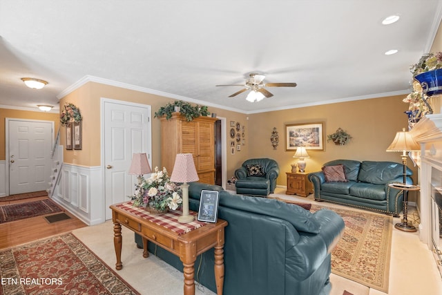 living room with crown molding, ceiling fan, and wainscoting