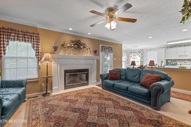 carpeted living room with crown molding, ceiling fan, a glass covered fireplace, recessed lighting, and baseboards