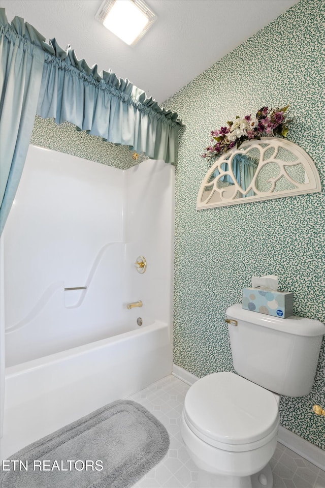 bathroom with toilet, wallpapered walls, and a bathtub