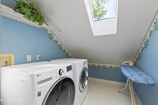 laundry room with a skylight, baseboards, laundry area, and washing machine and clothes dryer