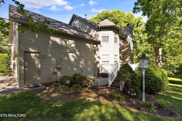 view of side of home with a yard and a chimney