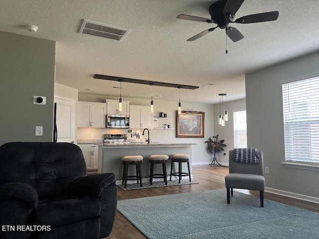 128 Waverly, Talbott, TN 37877 - living area with dark wood-style floors, visible vents, baseboards, a textured ceiling, and ceiling fan