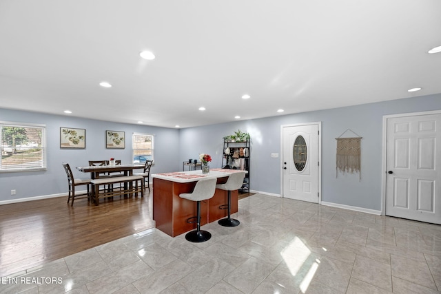 kitchen featuring baseboards, a wealth of natural light, light countertops, and a kitchen island