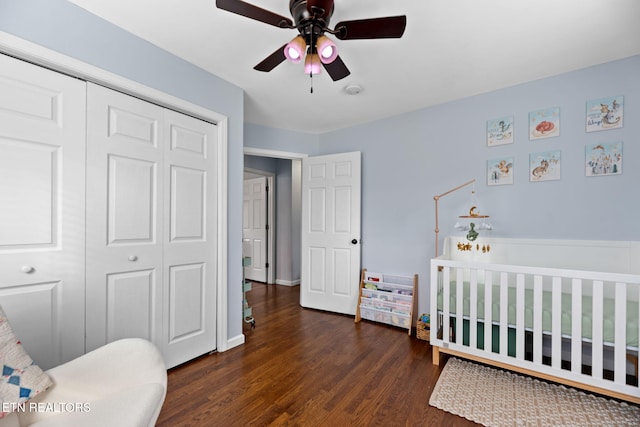 bedroom featuring wood finished floors, a closet, a crib, and ceiling fan