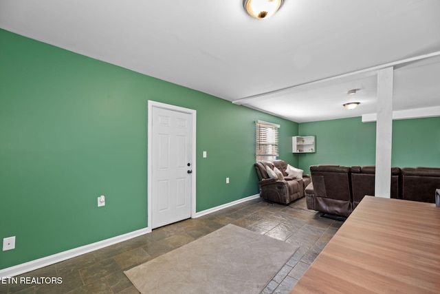 living room featuring stone tile floors and baseboards