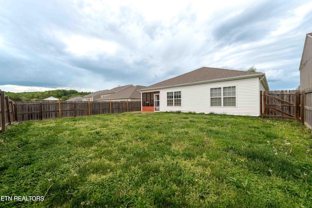 back of house with a lawn and a fenced backyard