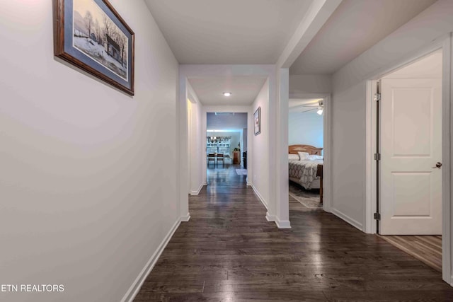 corridor featuring recessed lighting, baseboards, and dark wood-type flooring
