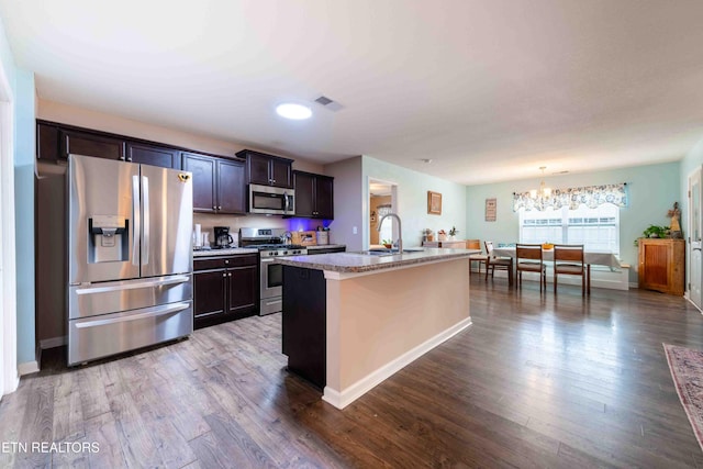 kitchen featuring stainless steel appliances, visible vents, a sink, and wood finished floors