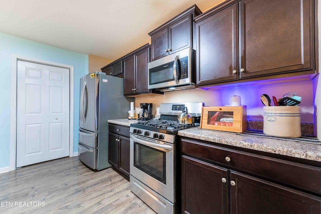 kitchen featuring stainless steel appliances, light wood finished floors, and dark brown cabinets