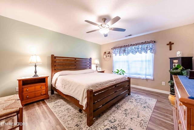 bedroom featuring visible vents, baseboards, ceiling fan, and wood finished floors