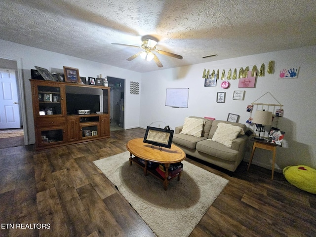 living area with visible vents, a ceiling fan, dark wood-style floors, and a textured ceiling