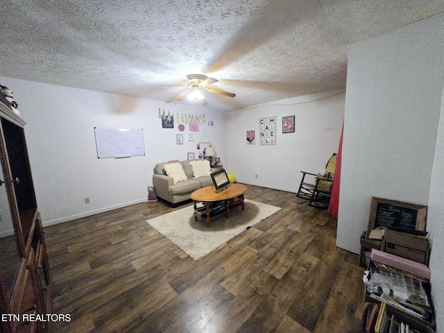 living area featuring dark wood-type flooring, a textured ceiling, and ceiling fan
