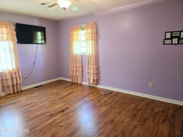 spare room with visible vents, baseboards, a ceiling fan, and wood finished floors