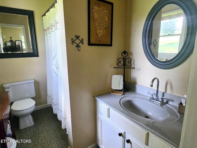 bathroom featuring baseboards, vanity, and toilet
