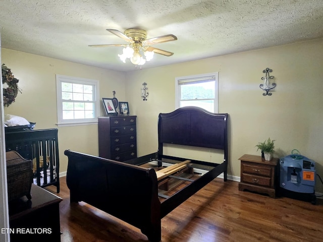 bedroom featuring wood finished floors, a textured ceiling, and baseboards