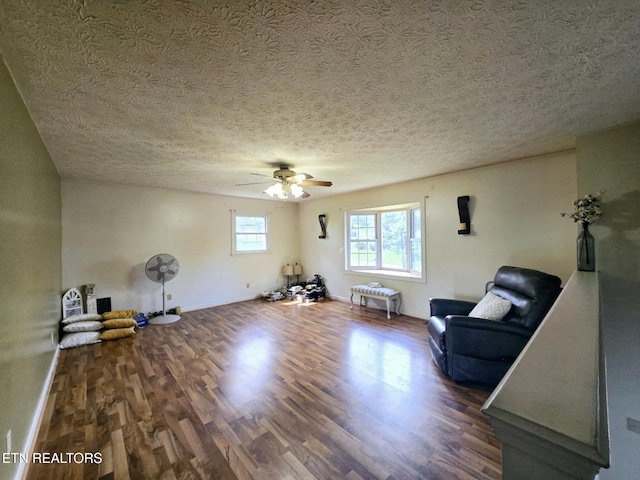 living area featuring wood finished floors, a textured ceiling, a ceiling fan, and baseboards