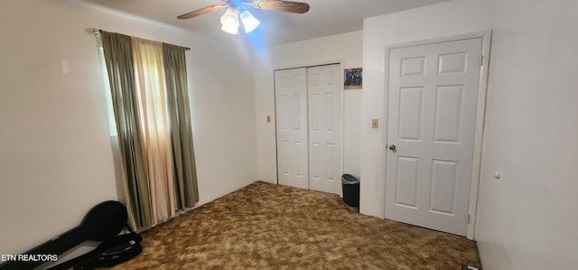 unfurnished bedroom with dark colored carpet, a closet, and ceiling fan