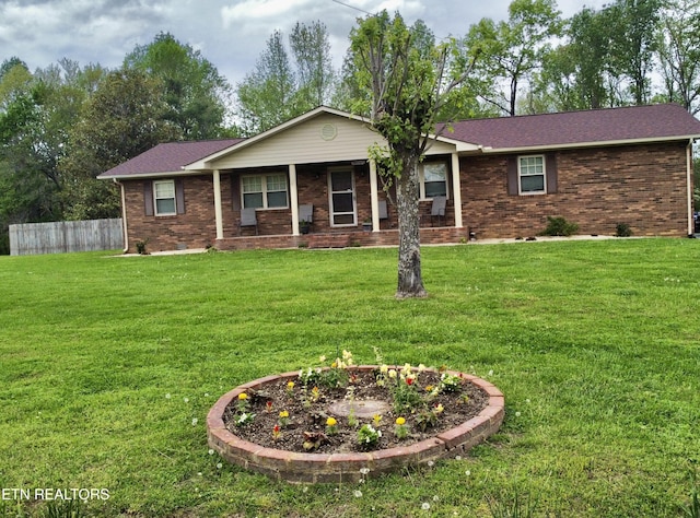 single story home featuring brick siding, fence, and a front yard