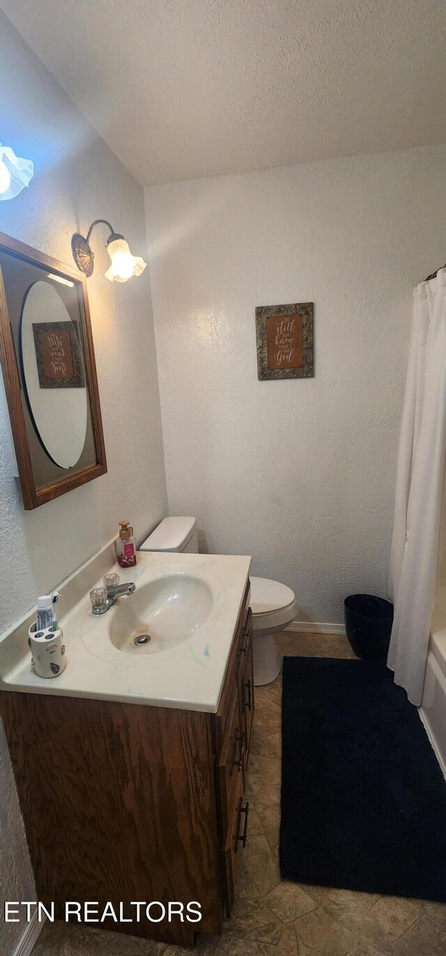 bathroom featuring toilet, shower / tub combo with curtain, vanity, and a textured ceiling