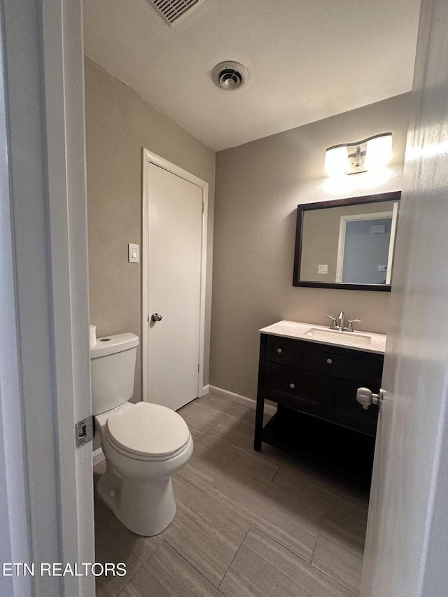 bathroom with visible vents, baseboards, vanity, and toilet