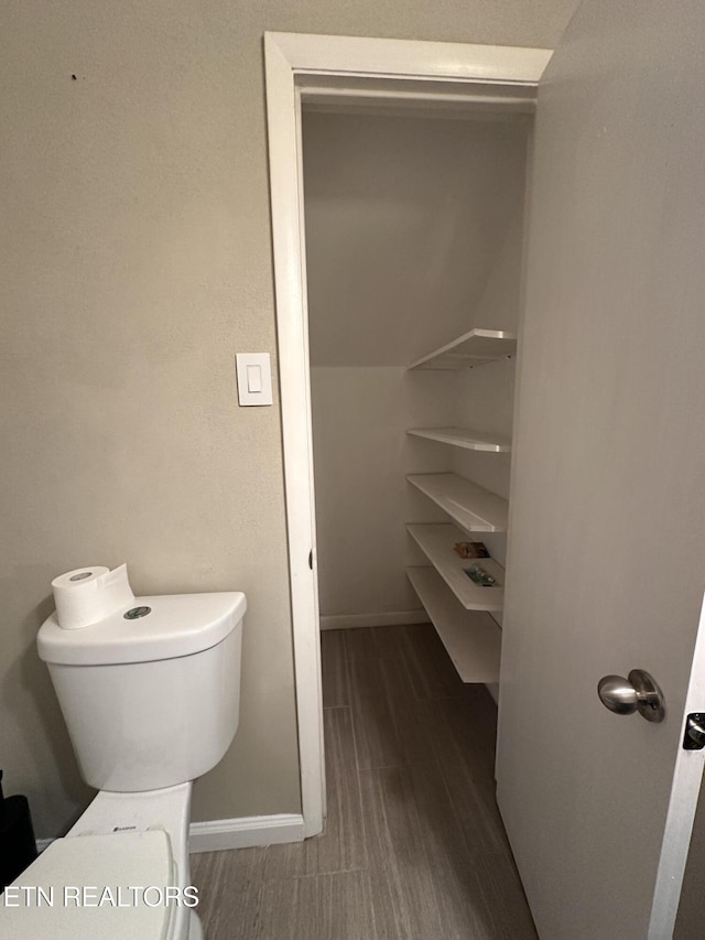 bathroom with toilet, wood finished floors, and baseboards