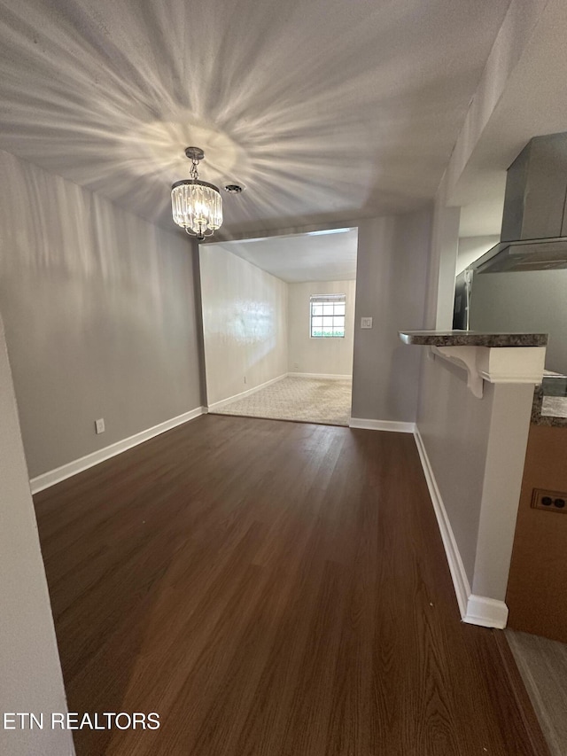 spare room with baseboards, a chandelier, and dark wood-type flooring