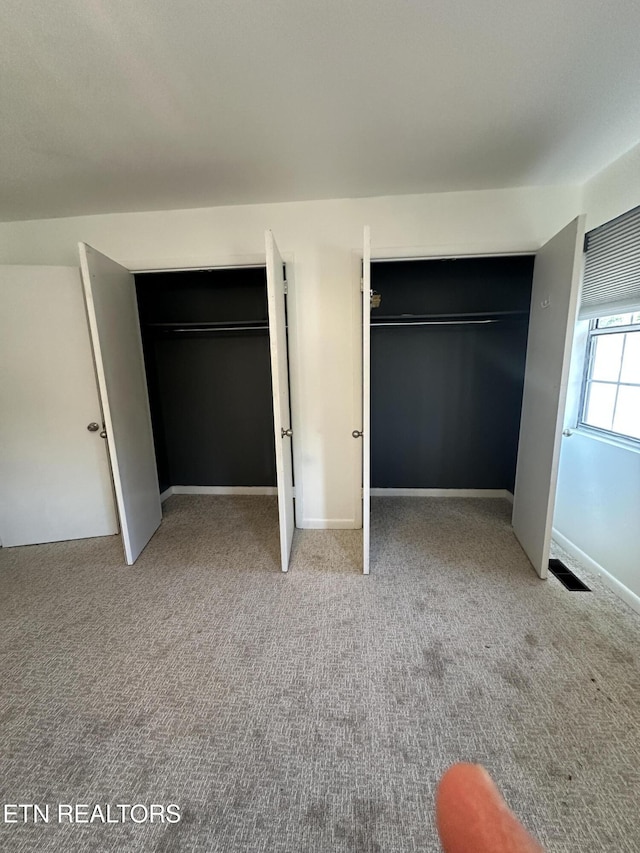 unfurnished bedroom with light carpet, visible vents, and baseboards