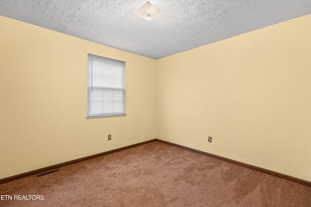 empty room with a textured ceiling, carpet floors, visible vents, and baseboards