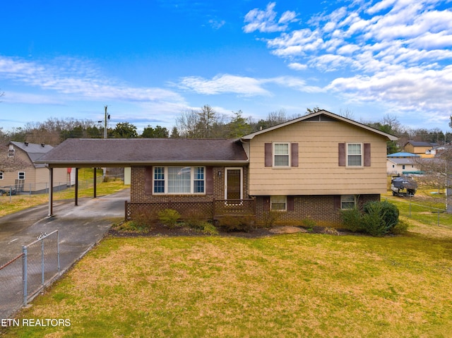 split level home with aphalt driveway, fence, a front lawn, an attached carport, and brick siding