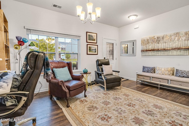 living area featuring baseboards, visible vents, wood finished floors, and an inviting chandelier
