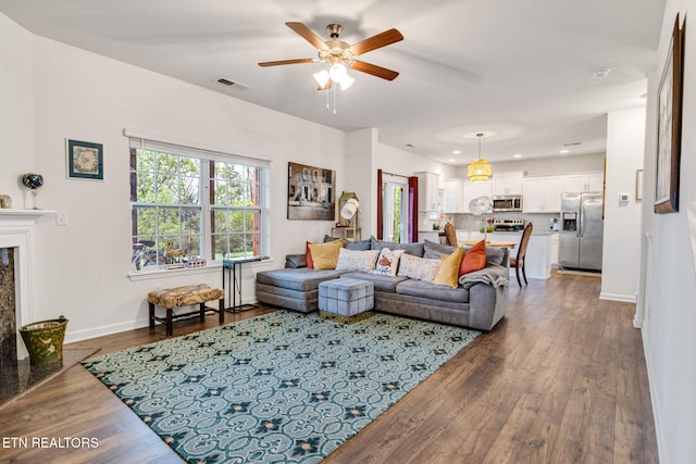 living room featuring dark wood finished floors, a ceiling fan, visible vents, and baseboards