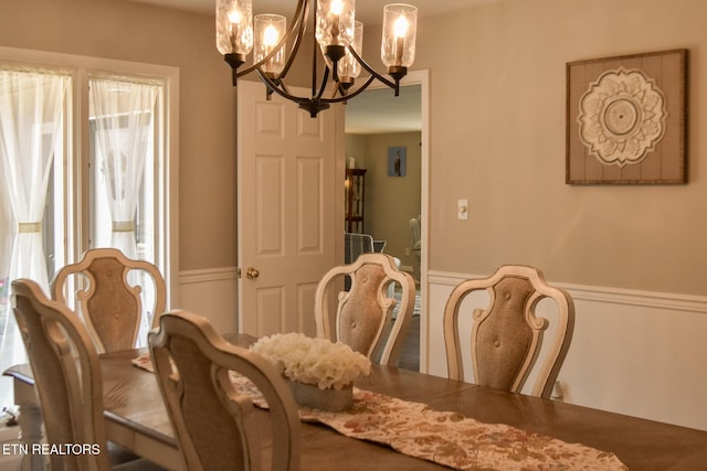 dining area featuring an inviting chandelier and a wainscoted wall