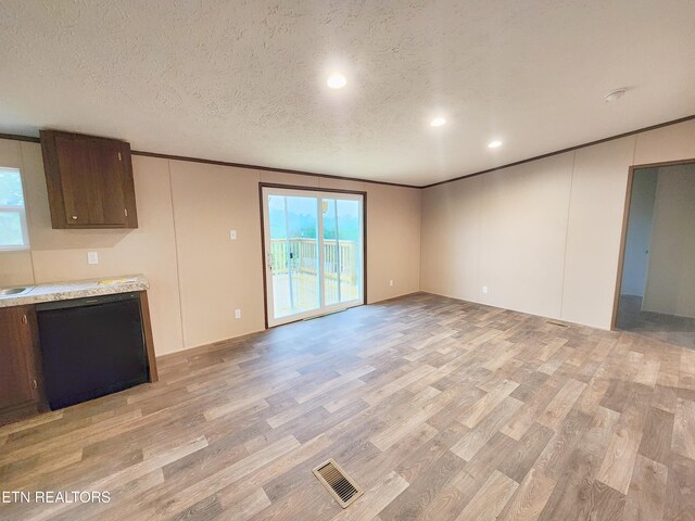 interior space with crown molding, light wood-style floors, a textured ceiling, recessed lighting, and visible vents