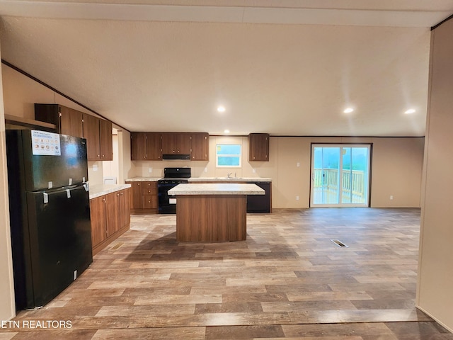 kitchen with light countertops, light wood-style flooring, black appliances, and a center island