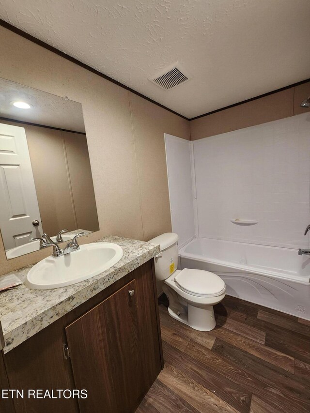bathroom featuring a textured ceiling, visible vents, wood finished floors, vanity, and toilet