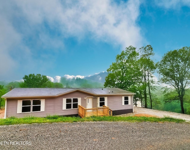 back of house with a wooden deck and dirt driveway