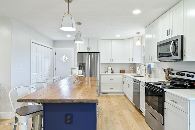 kitchen with a breakfast bar area, light wood-style floors, stainless steel appliances, and a sink