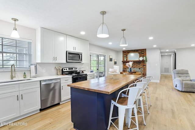 kitchen featuring a sink, appliances with stainless steel finishes, visible vents, open floor plan, and butcher block countertops
