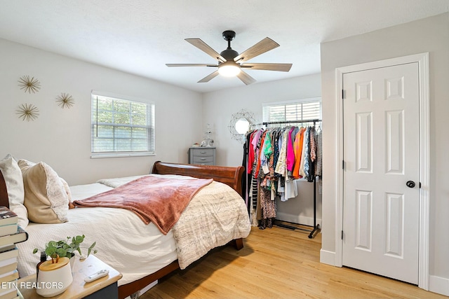 bedroom with baseboards, a ceiling fan, multiple windows, and light wood-style flooring