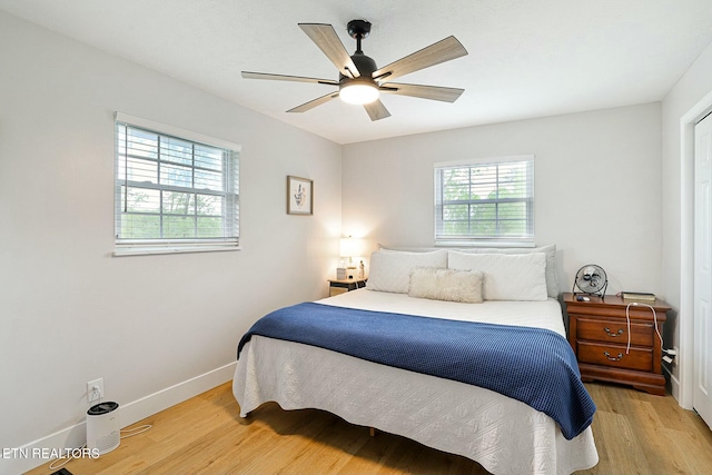 bedroom with light wood-style floors, ceiling fan, and baseboards