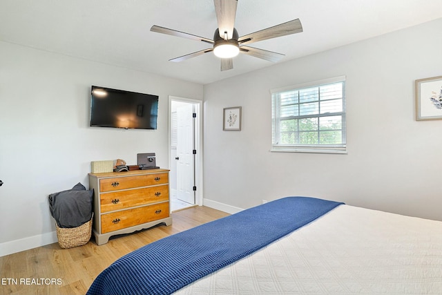 bedroom with light wood finished floors, a ceiling fan, and baseboards