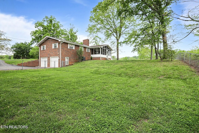 view of yard with a garage, fence, driveway, and a sunroom