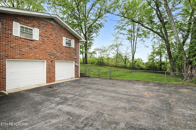 view of side of property with driveway, fence, and brick siding