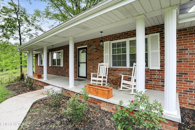 property entrance with a porch and brick siding